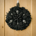 Black satin  & organza petals on a round wreath a large bow in middle 3 metallic spiderweb bows surround with glitter silver skulls in the center of bows and large ones between 
